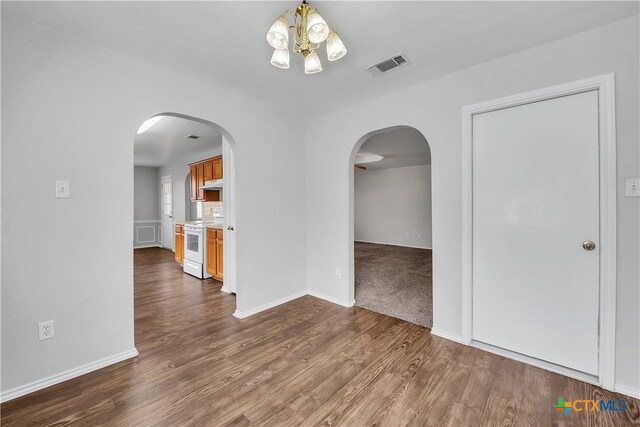 unfurnished room featuring dark wood-type flooring and an inviting chandelier