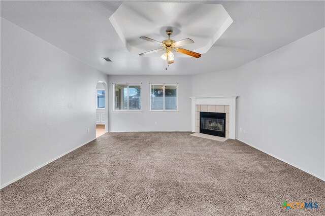 unfurnished living room with carpet floors, ceiling fan, and a tile fireplace