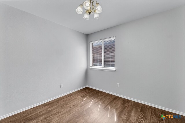 empty room with hardwood / wood-style floors and a chandelier