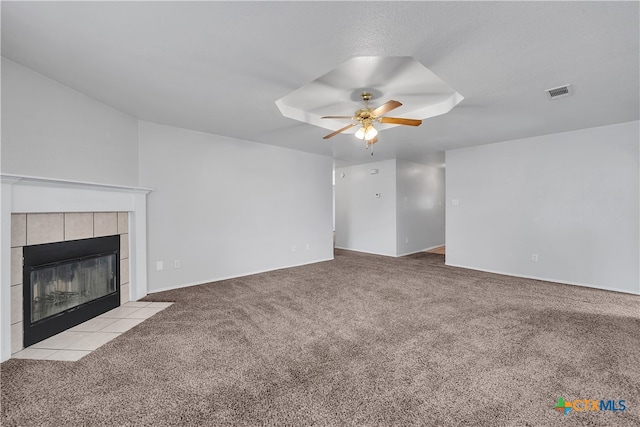 unfurnished living room featuring ceiling fan, a tiled fireplace, and light carpet