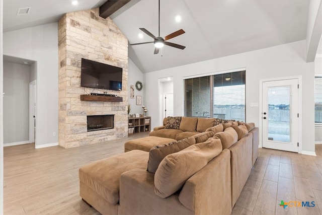 living room featuring a stone fireplace, beam ceiling, high vaulted ceiling, light hardwood / wood-style floors, and ceiling fan