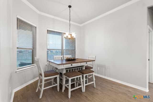 dining room featuring a notable chandelier, hardwood / wood-style flooring, and crown molding