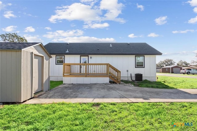 back of house with central AC, a yard, a storage shed, an outdoor structure, and a shingled roof