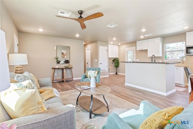 living area featuring recessed lighting, light wood-style floors, and visible vents