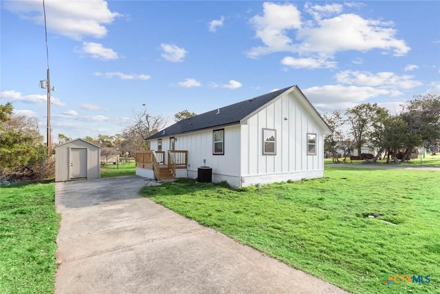 view of property exterior with an outbuilding, cooling unit, a yard, a storage unit, and board and batten siding