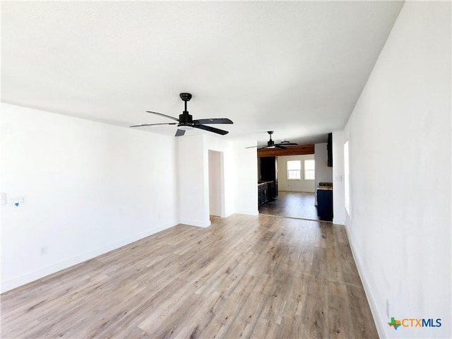 unfurnished living room featuring baseboards, light wood-type flooring, and a ceiling fan