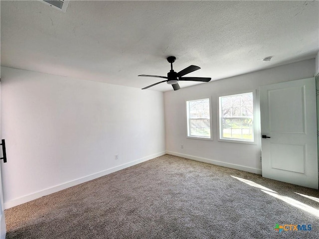 empty room featuring carpet flooring, a ceiling fan, a textured ceiling, baseboards, and visible vents