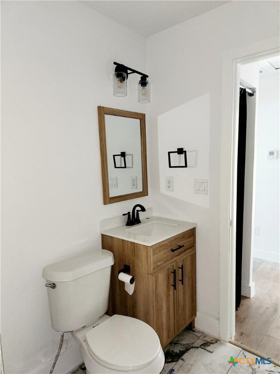 bathroom with marble finish floor, baseboards, toilet, and vanity