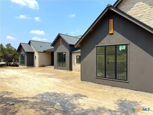 985 Malbec Loop, Canyon Lake, TX 78133 - view of property exterior featuring a standing seam roof, stucco siding, a metal roof, and stone siding