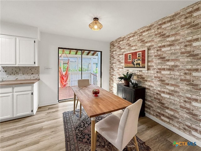 1412 Laurie Dr, Canyon Lake, TX 78133 - dining area with light wood-type flooring, brick wall, and baseboards