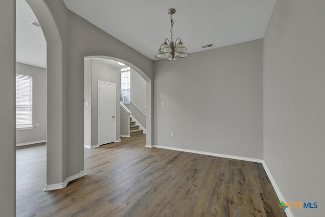 spare room featuring plenty of natural light, hardwood / wood-style floors, and an inviting chandelier