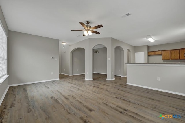 unfurnished living room featuring ceiling fan with notable chandelier and hardwood / wood-style flooring