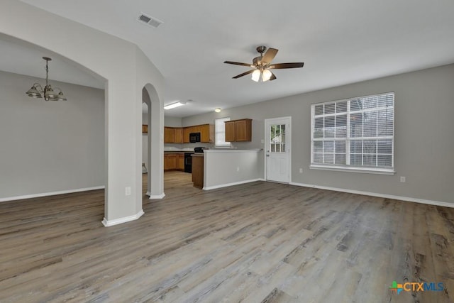 unfurnished living room with ceiling fan with notable chandelier and light hardwood / wood-style floors