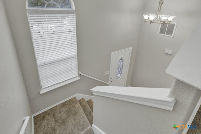 stairs with carpet and a notable chandelier