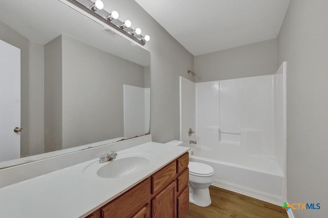 full bathroom featuring hardwood / wood-style floors, vanity, shower / bathtub combination, and toilet