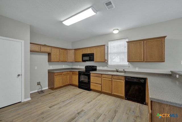 kitchen featuring black appliances, light wood-type flooring, and sink