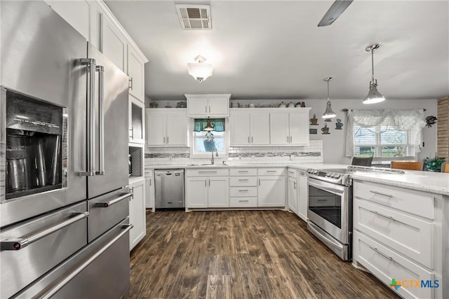 kitchen featuring backsplash, appliances with stainless steel finishes, hanging light fixtures, and white cabinets