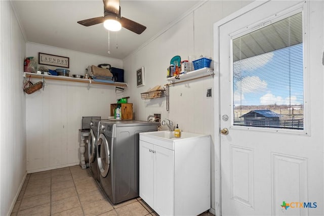 washroom with light tile patterned floors, crown molding, washer and clothes dryer, and cabinets