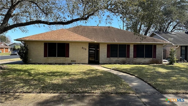 ranch-style home with a shingled roof, brick siding, and a front lawn