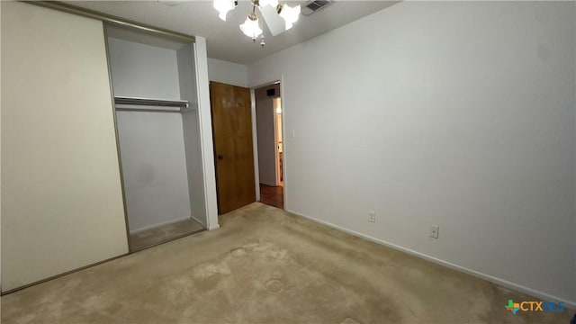 unfurnished bedroom featuring ceiling fan, a closet, carpet flooring, and visible vents