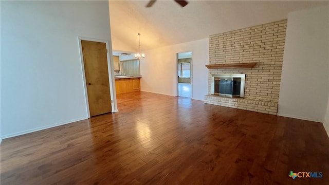 unfurnished living room with dark wood finished floors, a brick fireplace, high vaulted ceiling, baseboards, and ceiling fan with notable chandelier