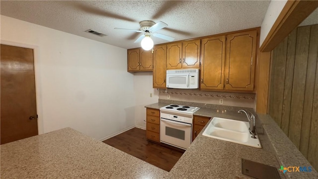 kitchen with white appliances, visible vents, brown cabinets, a textured ceiling, and a sink