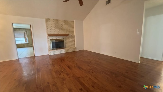 unfurnished living room featuring visible vents, a ceiling fan, lofted ceiling, dark wood-type flooring, and a brick fireplace