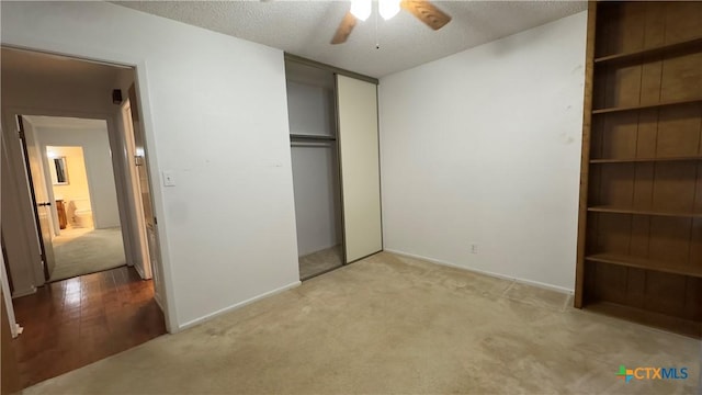 unfurnished bedroom with carpet floors, a closet, ceiling fan, and a textured ceiling