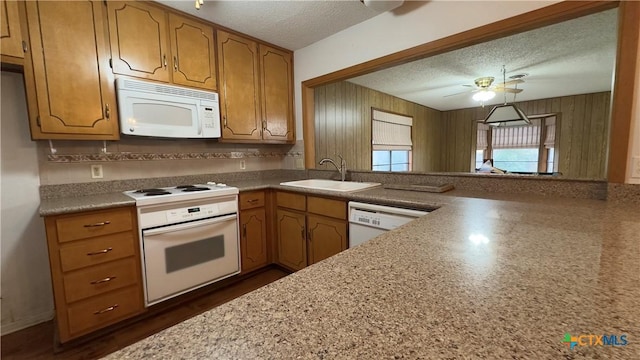 kitchen with white appliances, brown cabinetry, light countertops, a textured ceiling, and a sink