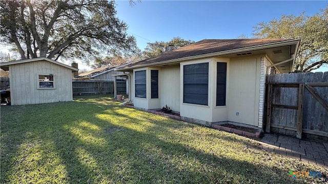 rear view of property featuring a fenced backyard, a yard, an outdoor structure, and a shed