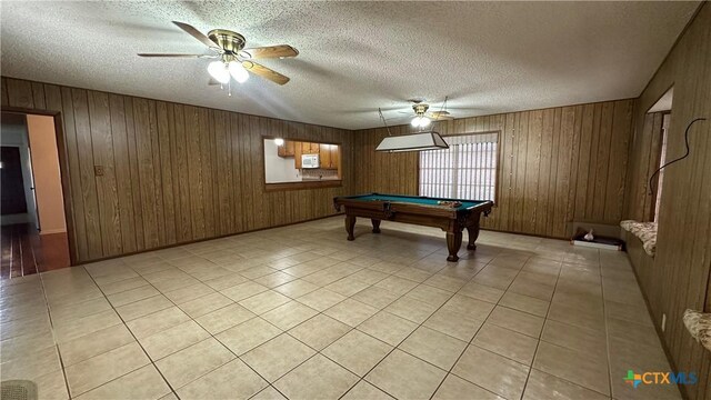 playroom featuring ceiling fan, wood walls, a textured ceiling, and billiards