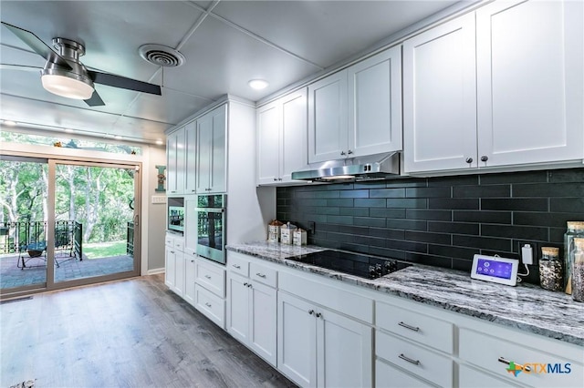 2518 Marlandwood Rd, Temple, TX 76502 - kitchen with stainless steel oven, visible vents, under cabinet range hood, black electric stovetop, and light wood finished floors