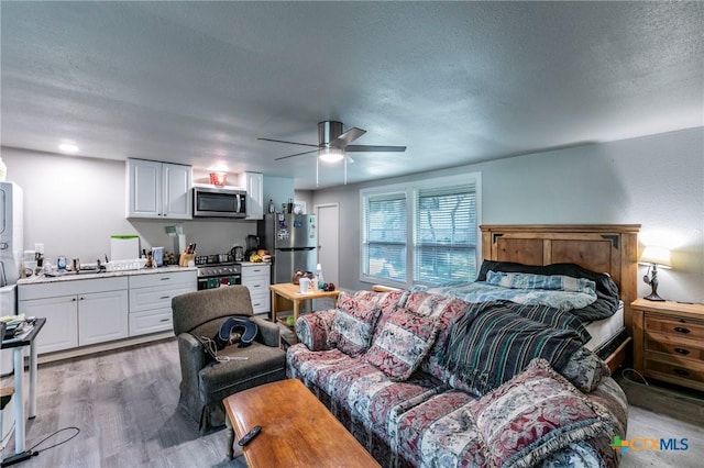 2518 Marlandwood Rd, Temple, TX 76502 - bedroom with light wood-style floors, a sink, freestanding refrigerator, and a textured ceiling