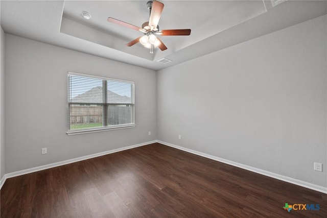618 Seven Springs Dr, Temple, TX 76502 - spare room with visible vents, baseboards, dark wood-style flooring, a ceiling fan, and a tray ceiling