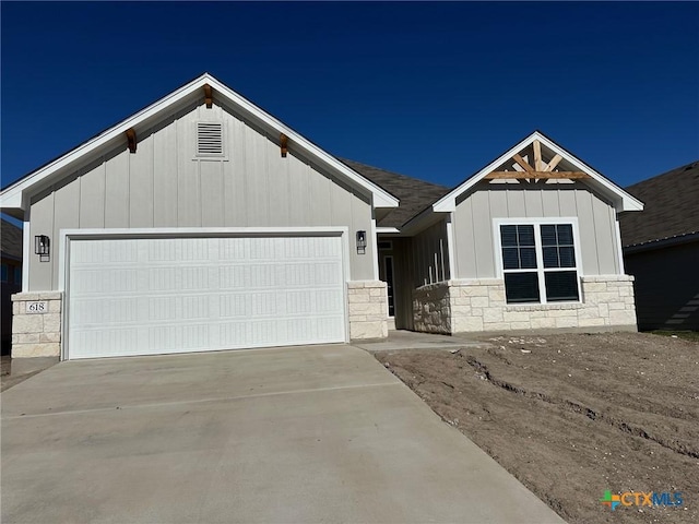 view of front of property with an attached garage, stone siding, driveway, and board and batten siding