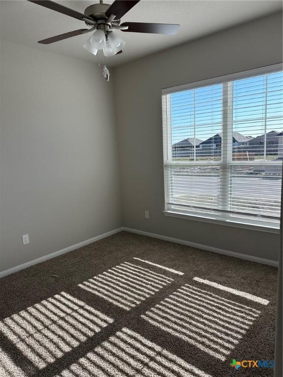 spare room with a ceiling fan, carpet flooring, and baseboards