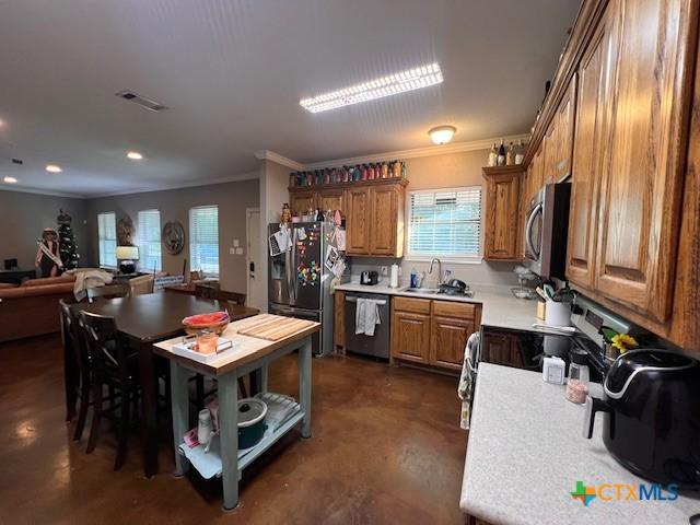 2800 S 3- A St, Waco, TX 76706 - kitchen with stainless steel appliances, ornamental molding, finished concrete floors, brown cabinets, and light countertops