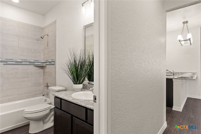 full bathroom featuring vanity, wood finished floors, bathing tub / shower combination, toilet, and a textured wall