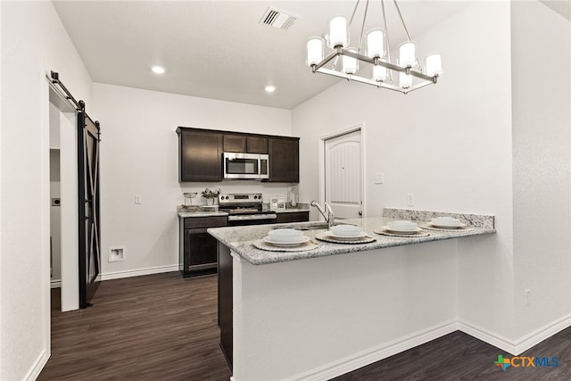 kitchen featuring visible vents, a sink, dark wood finished floors, stainless steel appliances, and a barn door