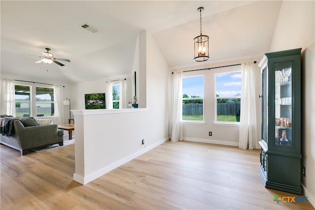 interior space featuring ceiling fan with notable chandelier, light wood-type flooring, and lofted ceiling