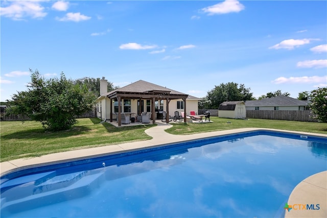 view of swimming pool featuring a lawn, a patio area, and a storage shed