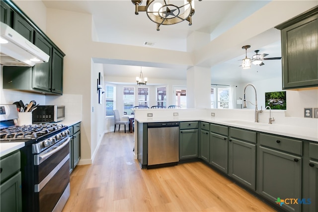 kitchen with ceiling fan with notable chandelier, sink, decorative light fixtures, kitchen peninsula, and stainless steel appliances