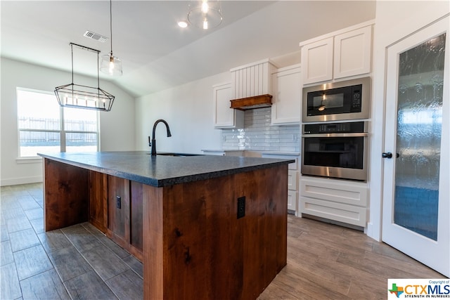 kitchen with stainless steel appliances, a center island with sink, white cabinets, sink, and dark hardwood / wood-style floors