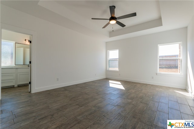 spare room featuring dark hardwood / wood-style flooring, a tray ceiling, and ceiling fan