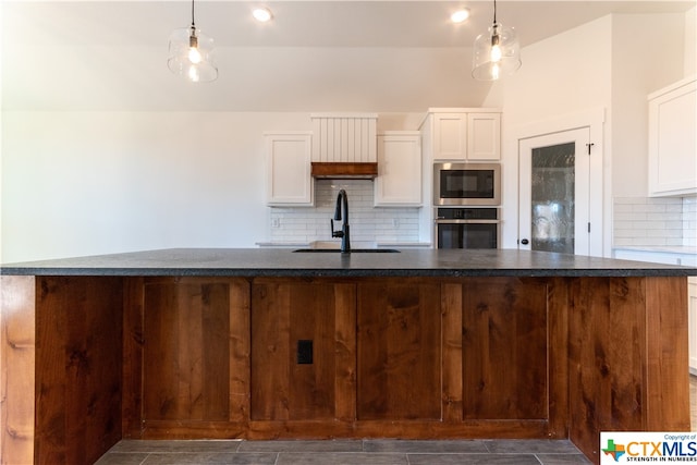 kitchen featuring stainless steel appliances, a center island with sink, and decorative light fixtures