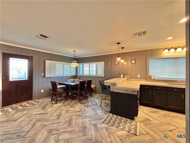 kitchen with crown molding, light parquet flooring, and hanging light fixtures