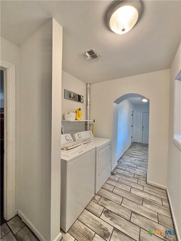 clothes washing area with washing machine and clothes dryer and light hardwood / wood-style flooring