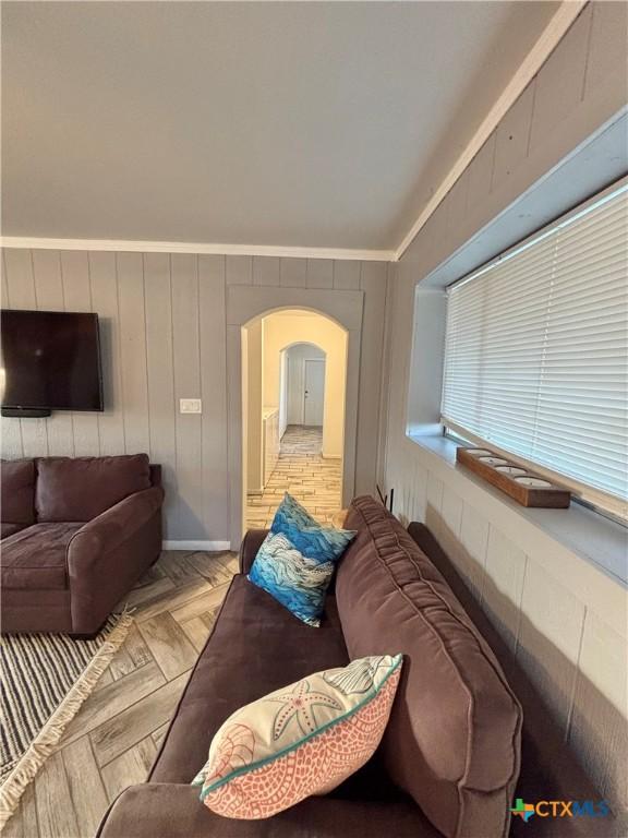 living room with wood walls, crown molding, and light parquet floors