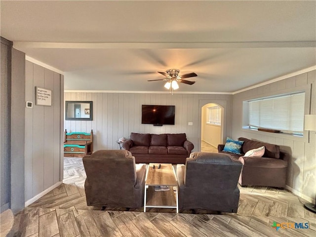 living room featuring ceiling fan, light parquet flooring, wood walls, and ornamental molding