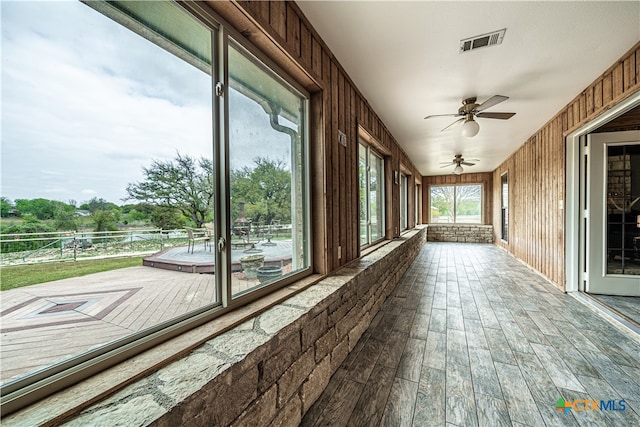 unfurnished sunroom featuring ceiling fan